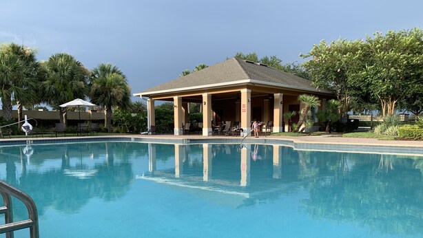 A clear swimming pool with a pavilion in the background.