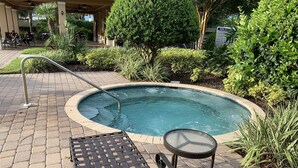 A pool area with a lounge chair, a small table, and a metal ladder leading into the pool.