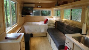 Una cabaña acogedora con cama, sofá y kitchenette.