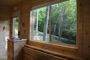 Enjoy a peaceful forest view from the comfort of this room, featuring a desk, telephone, and unique wall decor.