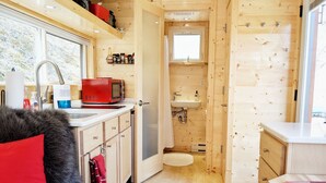 Una cabaña de madera acogedora con kitchenette, baño y zona de estar con una manta de piel.