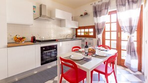 Una cocina moderna con armarios blancos, un horno negro y una mesa de comedor con sillas rojas.
