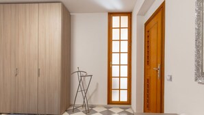 Un dormitorio con armario, tendedero, ventana y puerta.