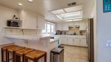 A kitchen with white cabinets, a countertop, and a trash bin.
