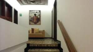 Un escalier aux marches décorées mène à une pièce où se trouve un canapé beige et un tableau accroché au mur.
