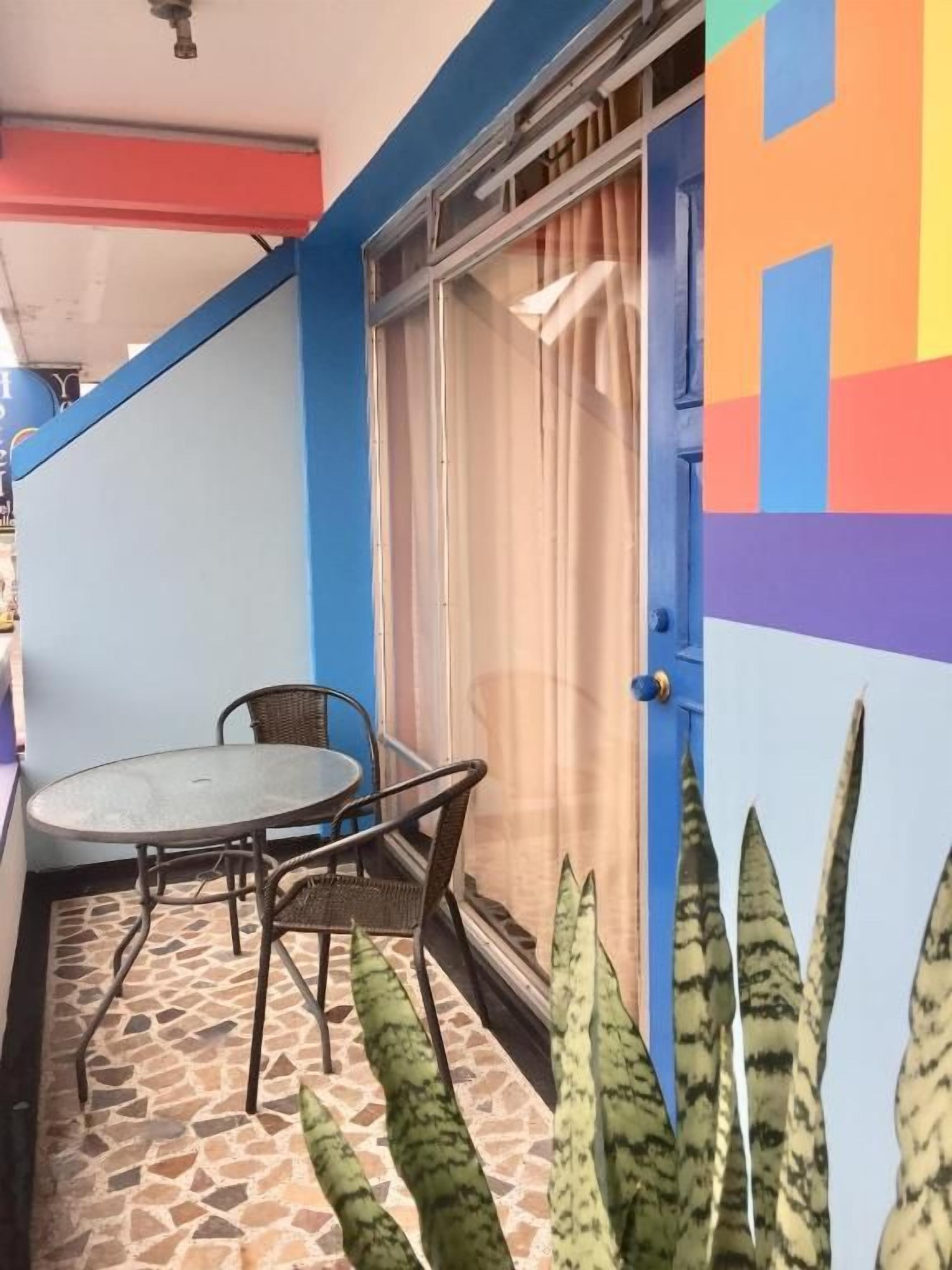 A small outdoor seating area with a table and chairs, a sliding glass door, and a tiled floor.