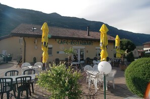 Un café doté d’une terrasse et de parasols jaunes, entouré de montagnes.