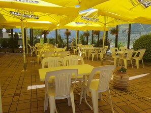 Un espace extérieur aménagé avec des parasols jaunes et des chaises en plastique blanches.