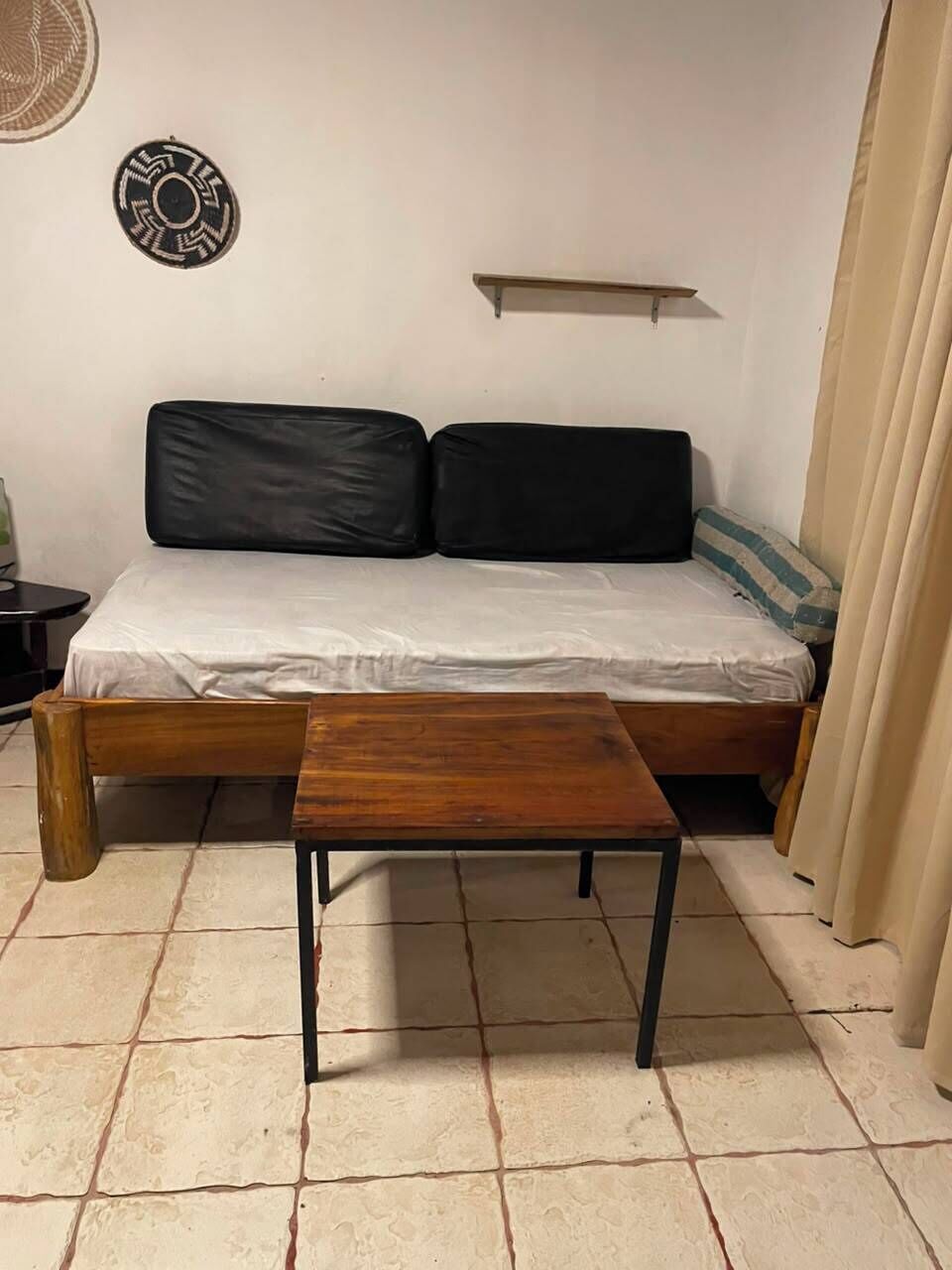 Una camera con un letto, un tavolo di legno, una mensola a muro e una decorazione murale a motivi.