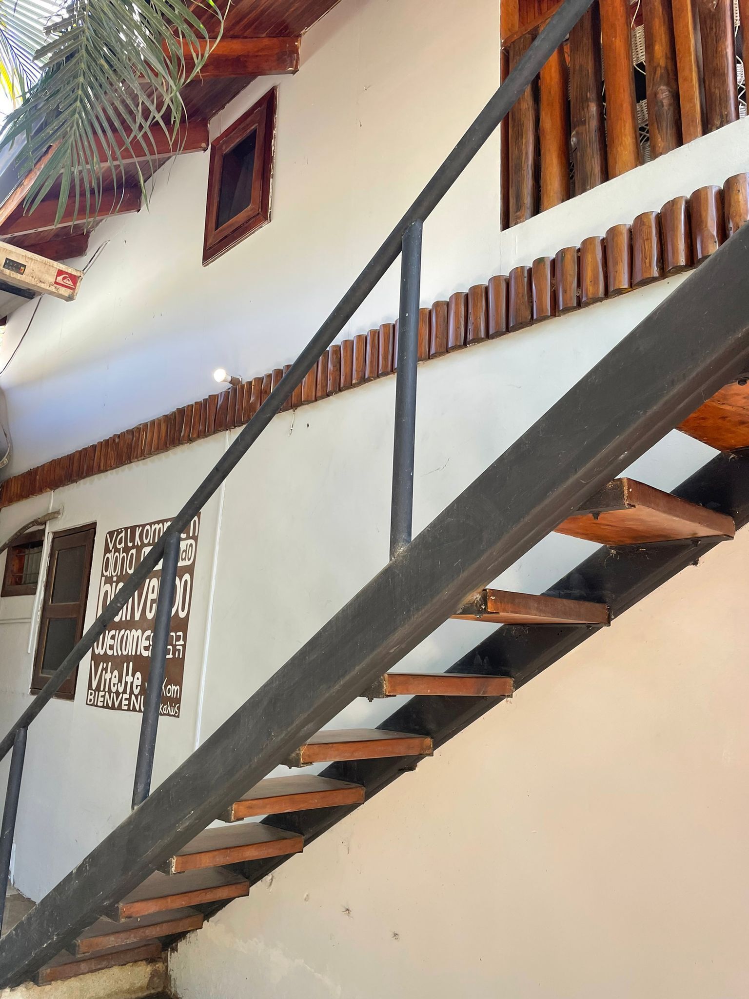 Una escalera de madera con barandillas de metal que conduce a una pared blanca con un letrero de bienvenida.