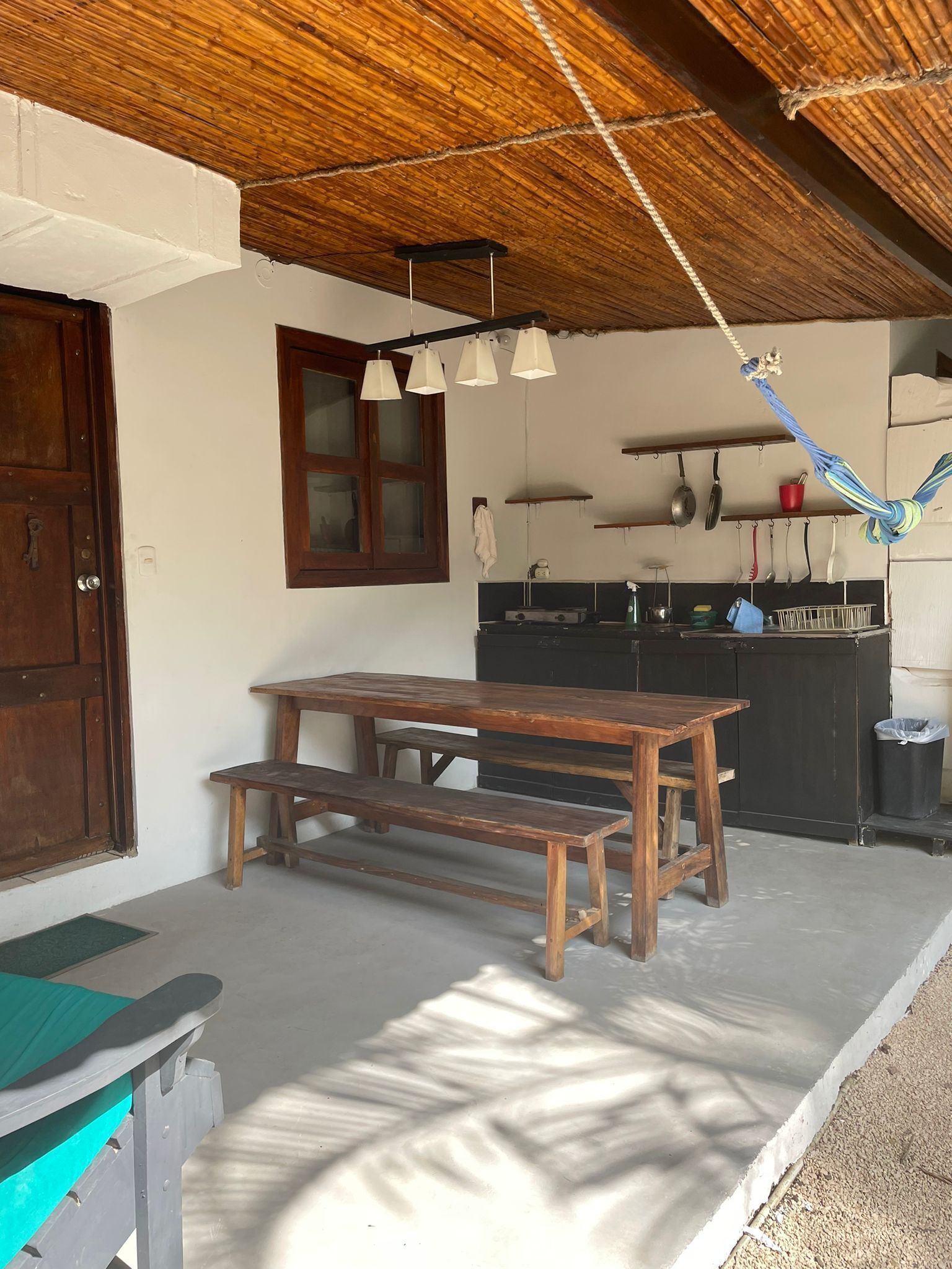 Une cuisine rustique avec une table et un banc en bois, un luminaire suspendu et une fenêtre avec un cadre en bois.