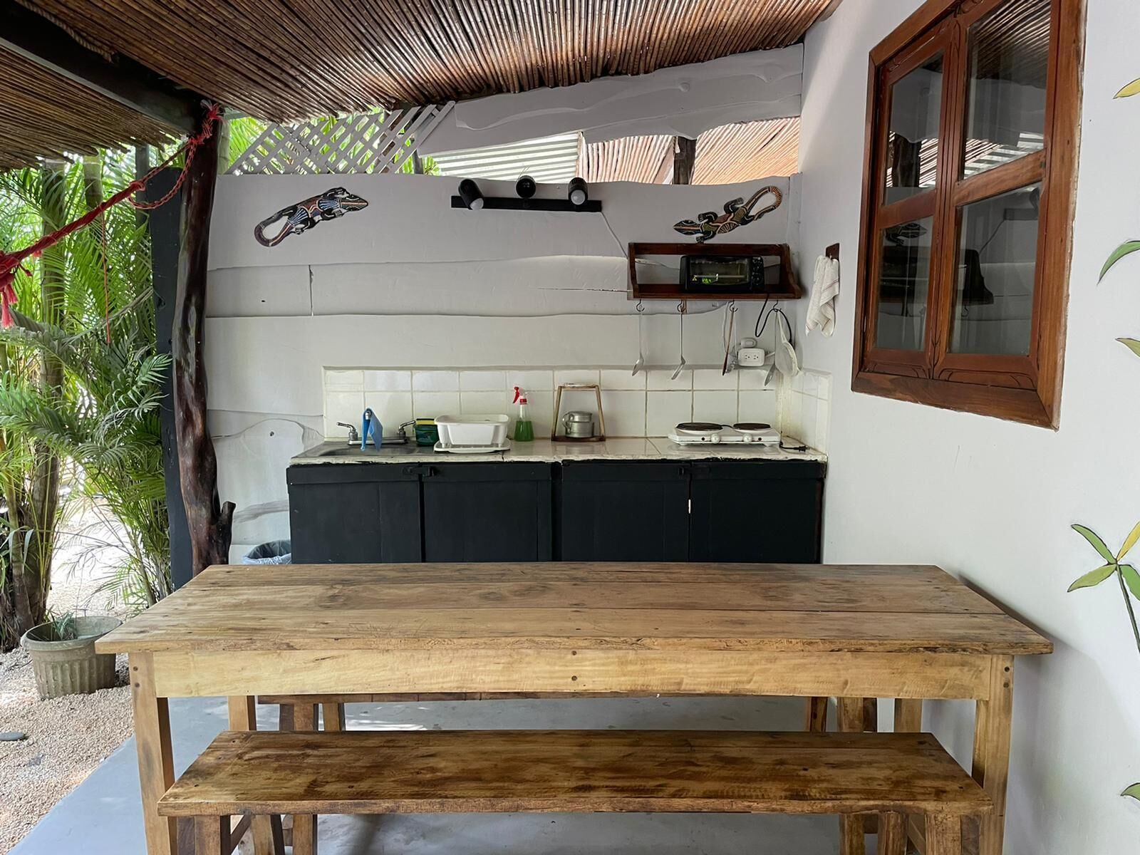 A kitchen with a wooden table and bench, a microwave, and a sink.
