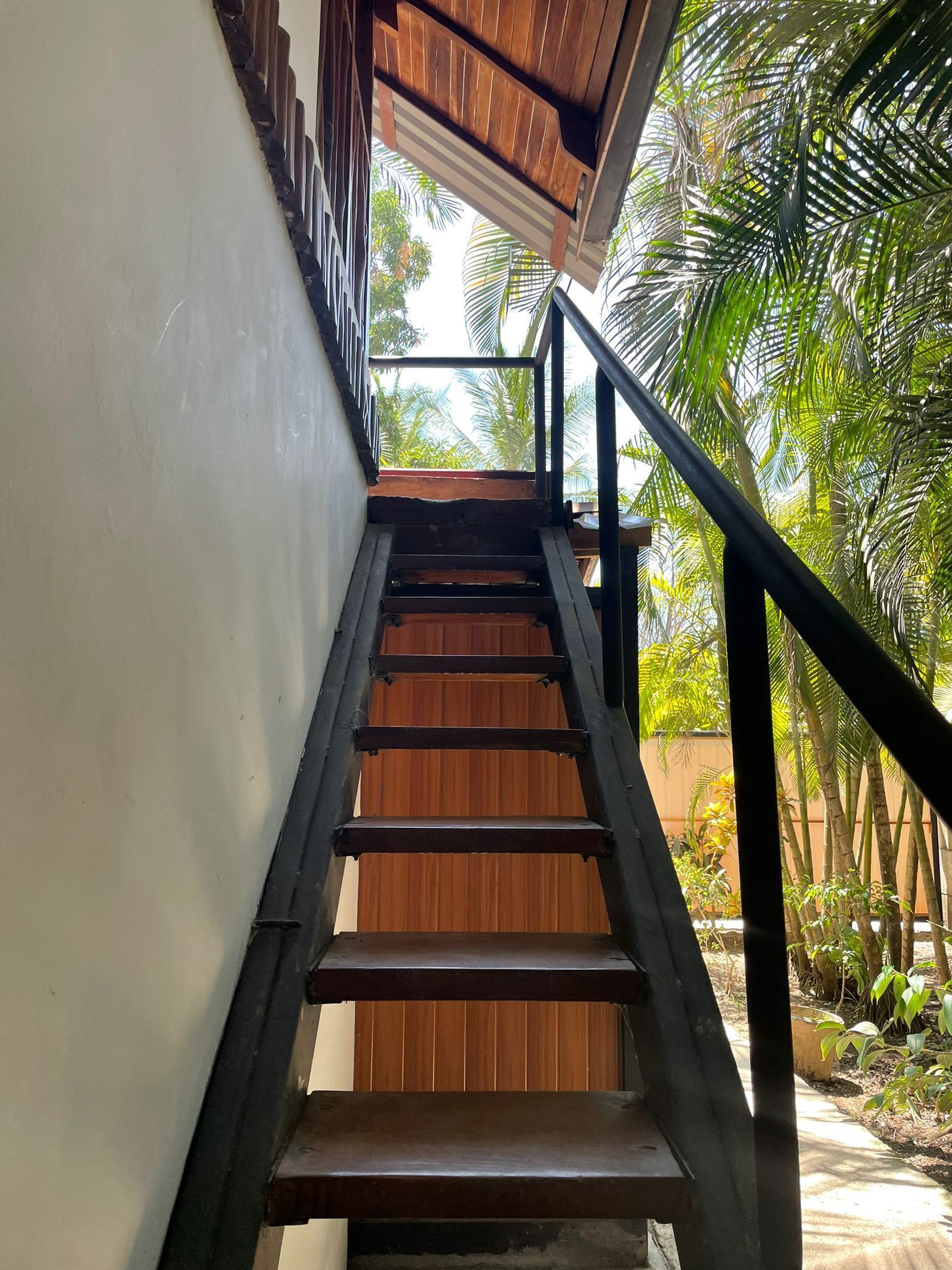 A wooden staircase with black railings leading to a wooden door.