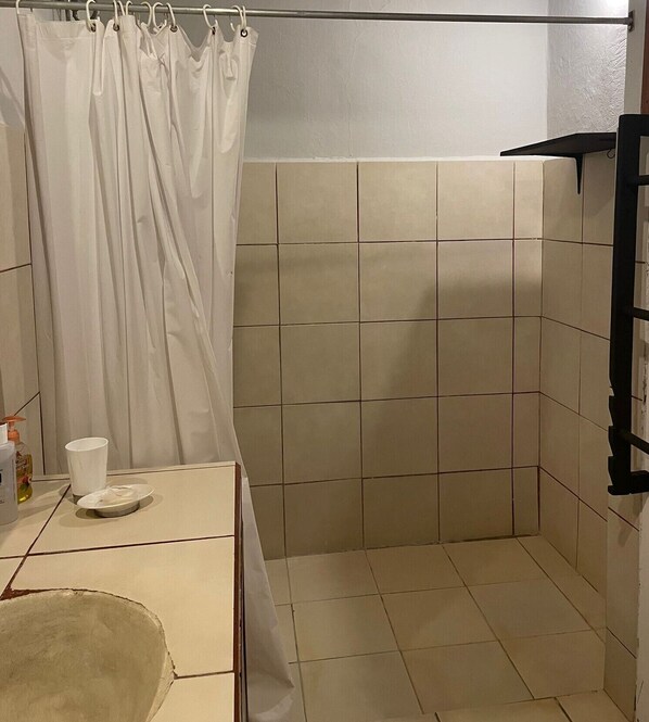 Une salle de bain avec des carreaux de couleur beige, un rideau de douche blanc et un porte-serviettes.