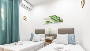 A hotel room with two beds, a nightstand, a lamp, and a wall-mounted air conditioner. - HOUSE OF LIGHT apt 1 -Elegant Old Town 3PX wifi tv ac (Sevilla)