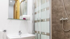 A bathroom with a white sink, a glass shower enclosure, and a showerhead. - HOUSE OF LIGHT apt 1 -Elegant Old Town 3PX wifi tv ac (Sevilla)