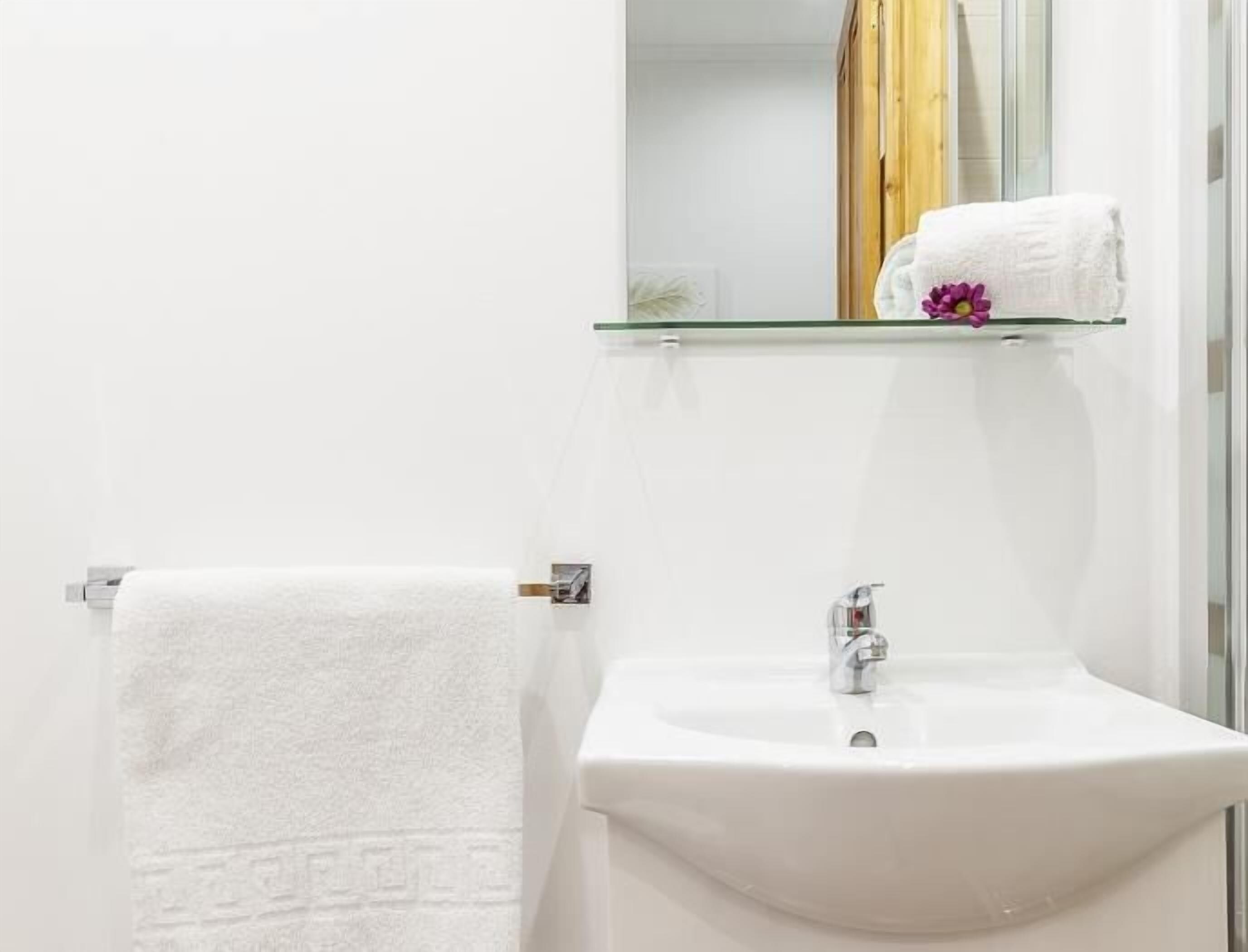 A bathroom with a white sink, a towel hanging on a rack, and a mirror above the sink.