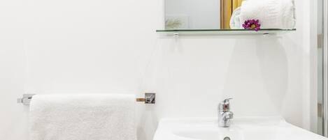 A bathroom with a white sink, a towel hanging on a rack, and a mirror above the sink.