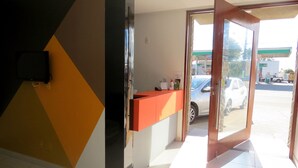 A hotel reception area with a counter, a television mounted on the wall, and a view of the parking lot outside.
