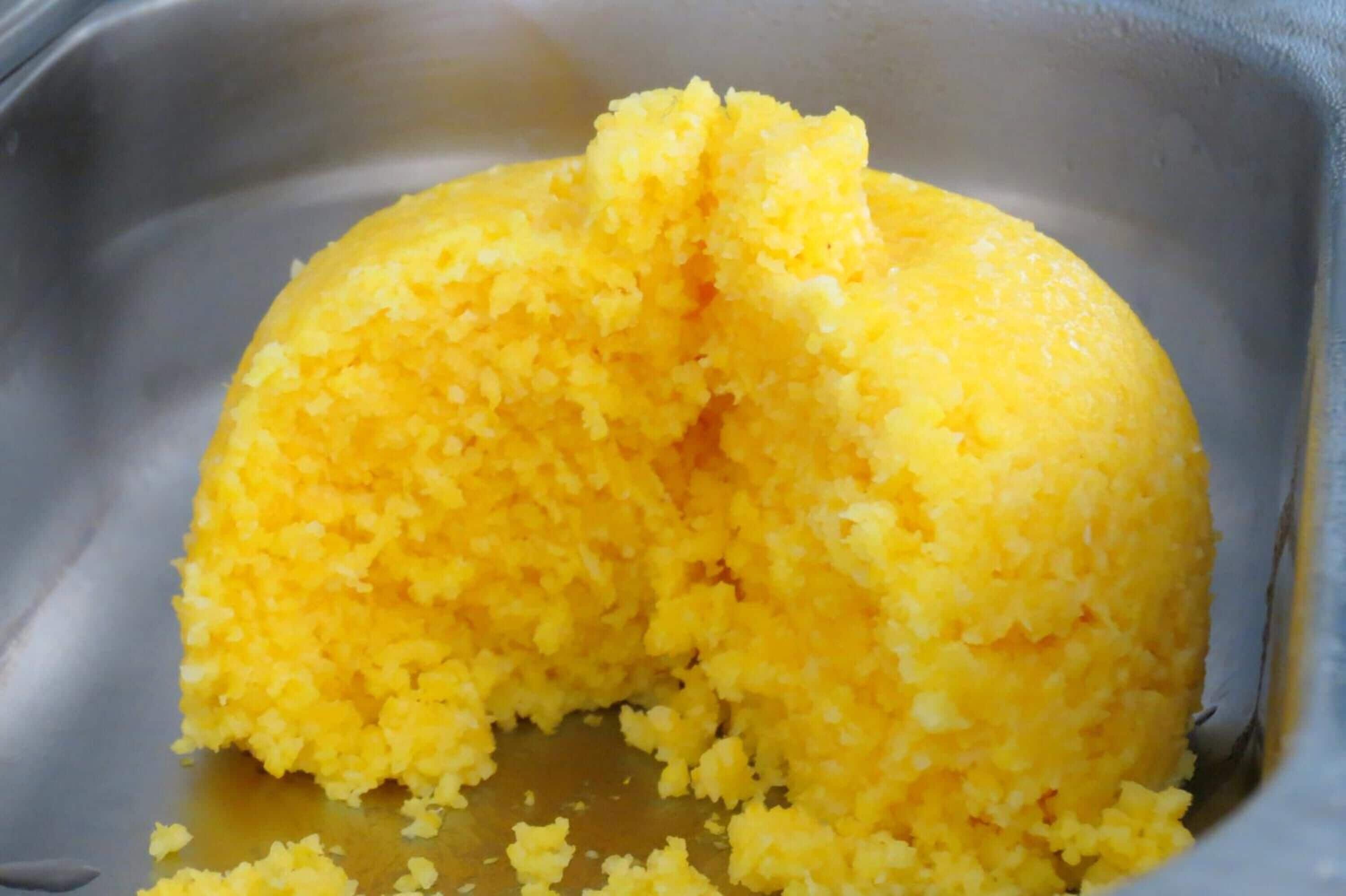 Un alimento amarillo y con textura en un recipiente metálico.
