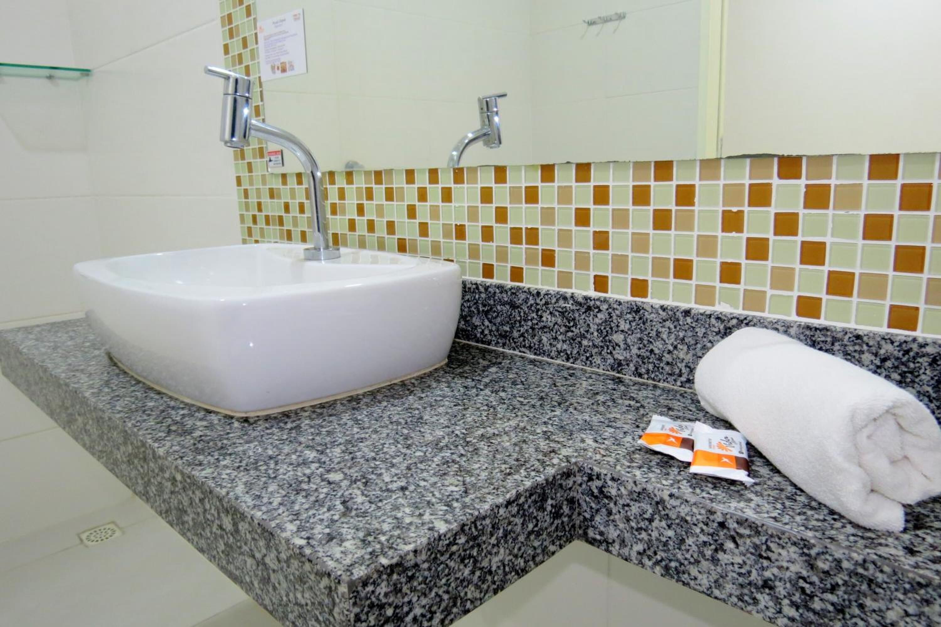 A bathroom with a white sink, granite countertop, and a towel on the counter.