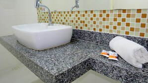 A bathroom with a white sink, granite countertop, and a towel on the counter.