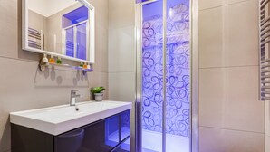 Et moderne badeværelse med hvid vask, spejl, brusekabine i glas og toilet.