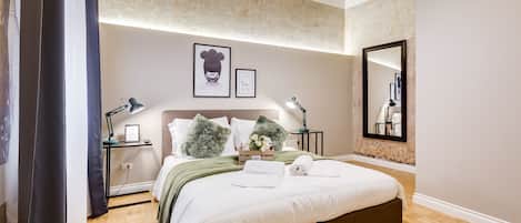 A modern bedroom with a large bed, wooden flooring, and a ceiling with exposed beams.