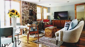 A cozy living room with a stone fireplace, a television, and comfortable seating. - The Perfect Catskills Lake House (Yulan)