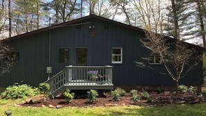 A two-story house with a front porch, a small garden, and a wooden deck. - The Perfect Catskills Lake House (Yulan)