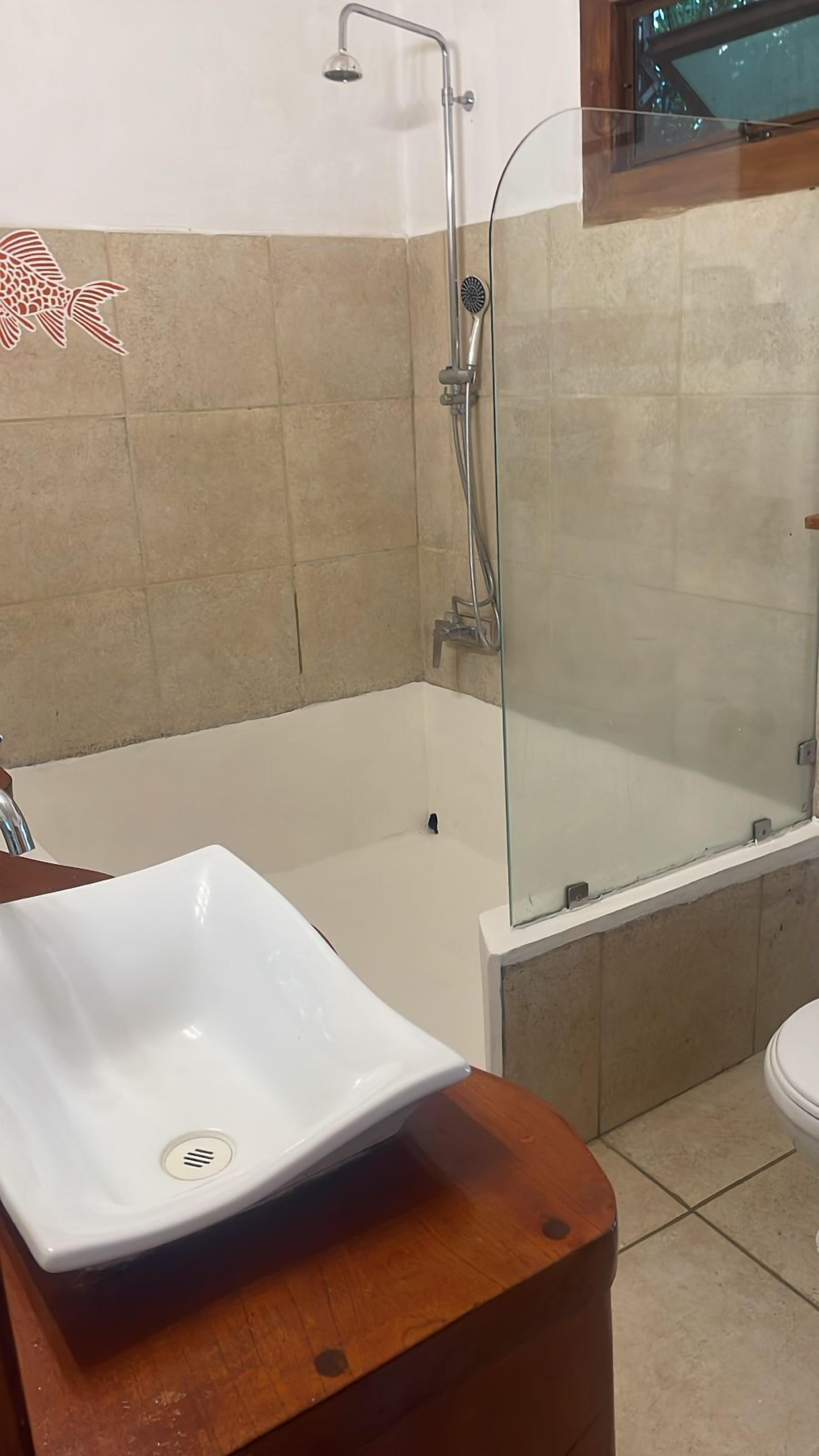 A bathroom with a bathtub, a glass-enclosed shower, and a white sink on a wooden countertop.