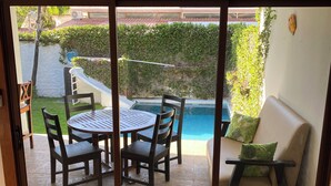 Una stanza con una porta scorrevole in vetro che dà su un’area esterna con piscina, un tavolo e sedie, e un divano.
