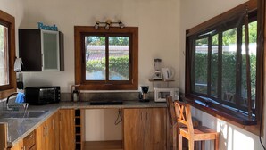 Una cucina con mobili in legno, forno integrato, macchina per caffè e finestra con vista sul verde.