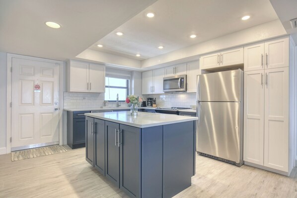 A modern kitchen with a central island, stainless steel appliances, and white cabinetry.