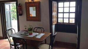 A dining area with a wooden table, four chairs, a potted plant, and a wall-mounted mirror.