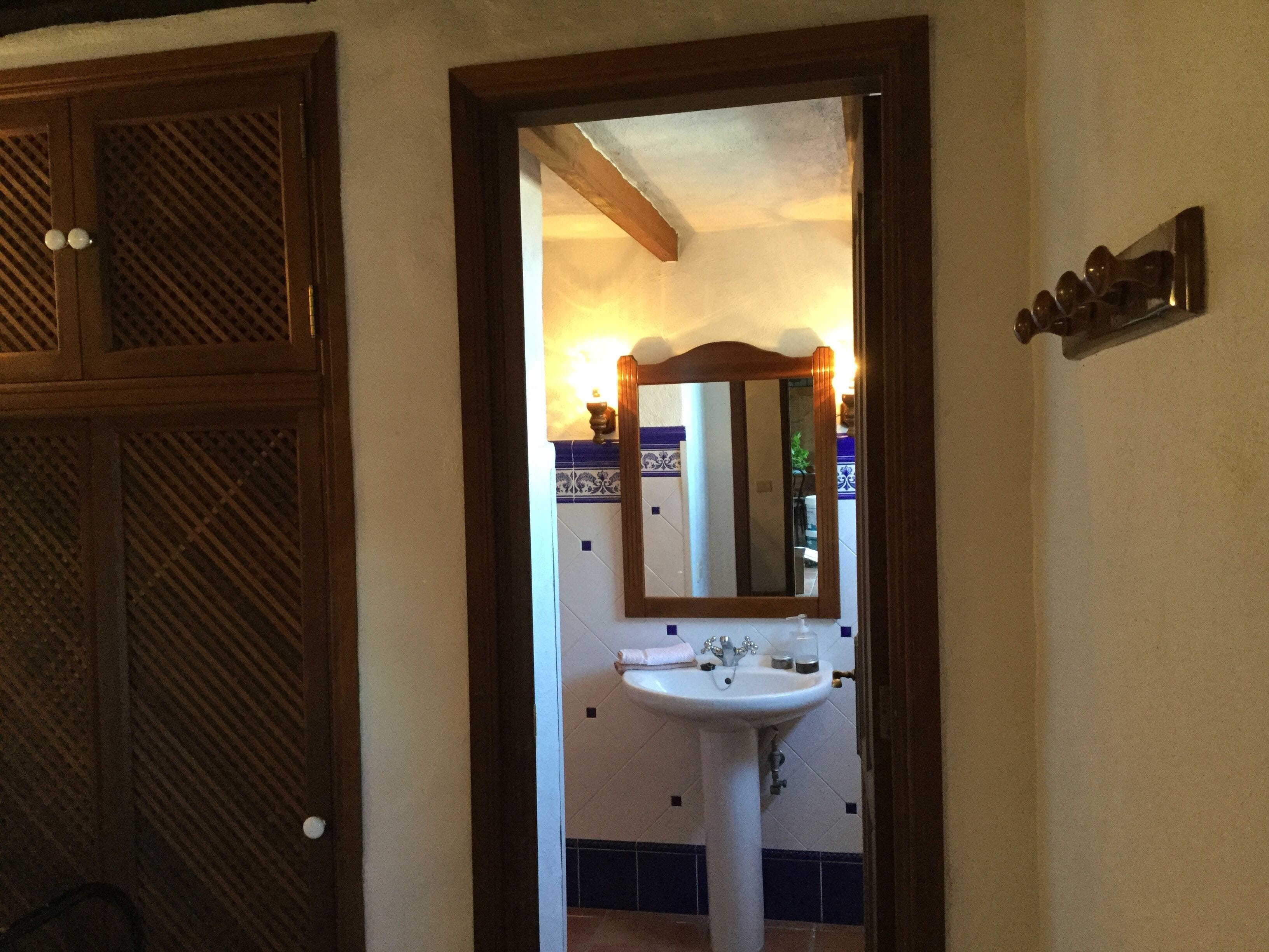 Un baño con puerta de madera, lavamanos blanco y espejo.