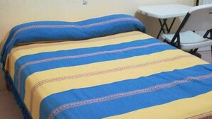 A bed with a blue and yellow striped bedspread and matching pillows. - Amplias y Confortables Habitaciones (San Juan Bautista Tuxtepec)