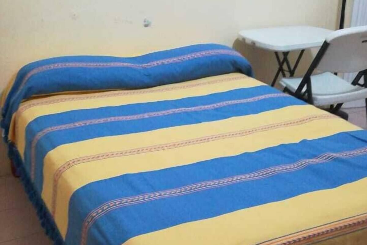 Ein Bett mit einer blau-gelb gestreiften Tagesdecke und passenden Kissen.