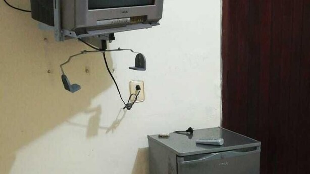 A television mounted on a wall with a small refrigerator below it. - Amplias y Confortables Habitaciones (San Juan Bautista Tuxtepec)