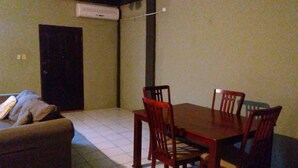 Un espace repas comprenant une table et des chaises en bois, un canapé et une porte.