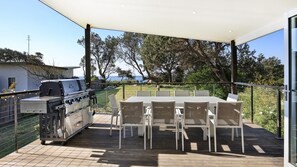 Eine Terrasse im Freien mit Grill, Tisch und Stühlen.
