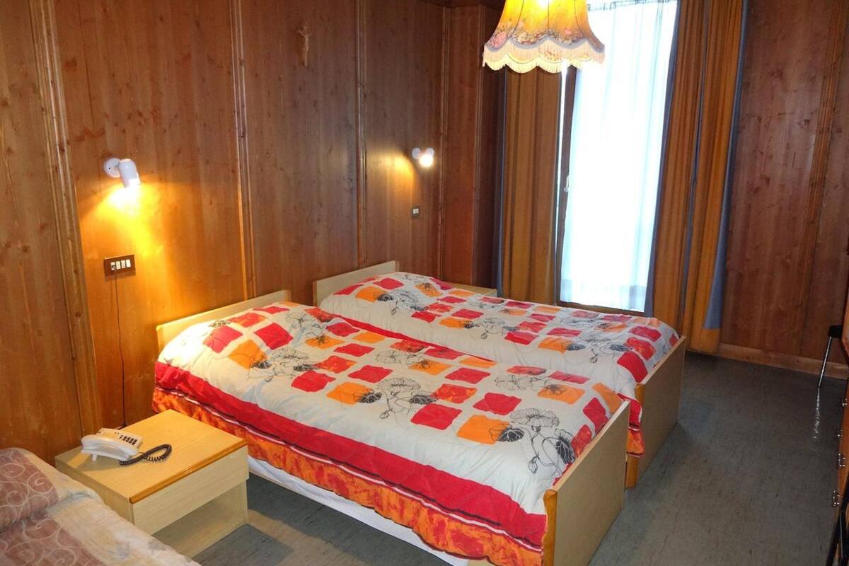 A double bed with floral bedding, a bedside table with a phone, and a lamp.