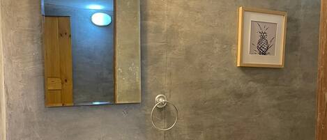 A bathroom with a large white sink, a mirror, a framed pineapple artwork, and a towel rack.