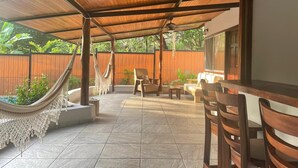 Un patio al aire libre con suelo de madera, una hamaca y mobiliario para sentarse.