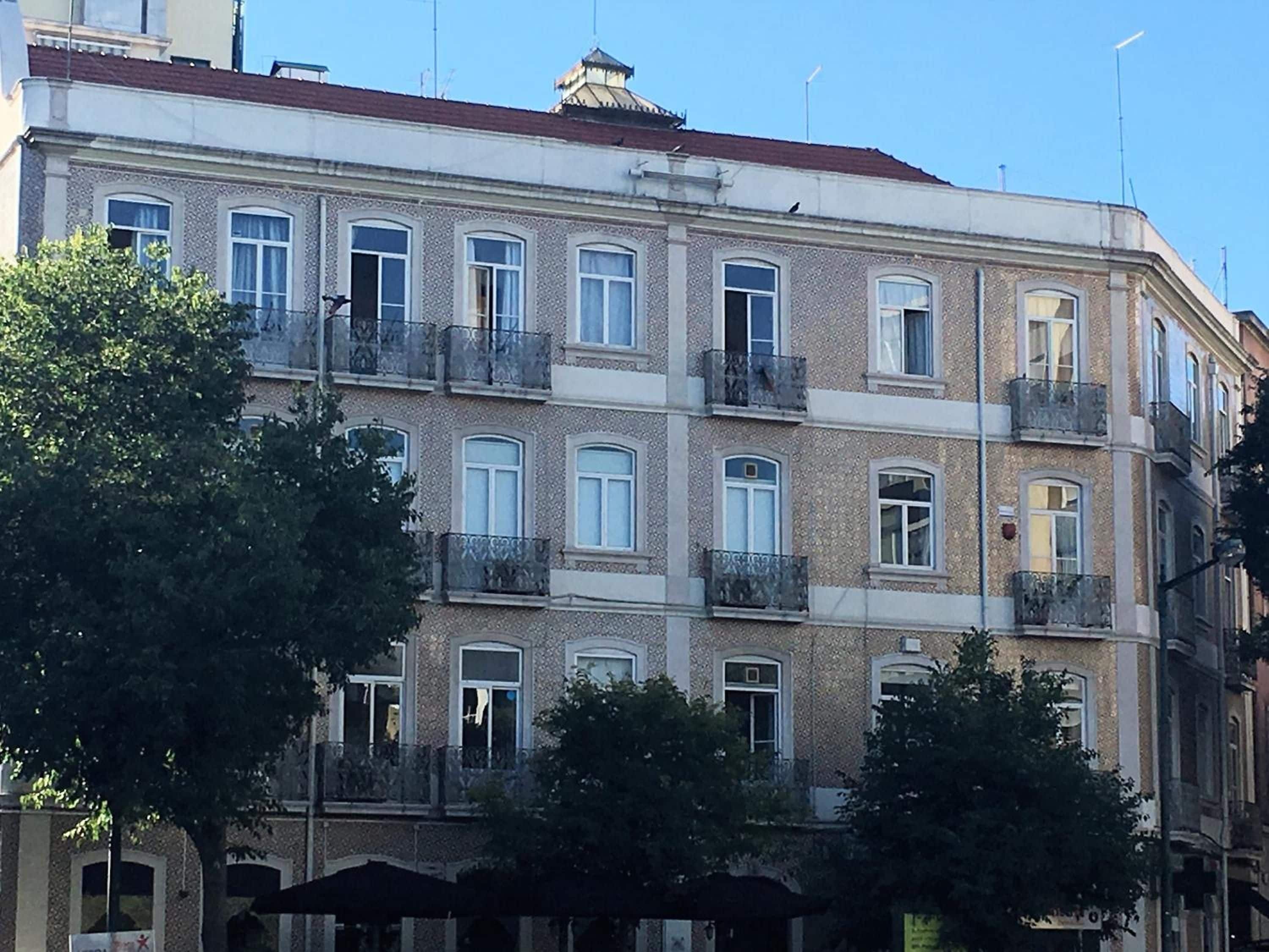 A multi-story building with balconies, large windows, and a traditional architectural style.