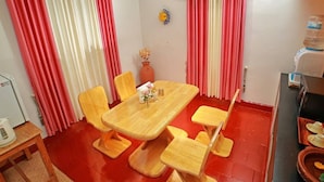 A dining area with a wooden table and chairs, a vase with flowers, and a water dispenser.