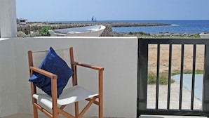 A balcony with a view of the sea, a boat, and a chair with a blue pillow. - Enchanting fisherman’s cottage in front of the sea in Biniancolla (Biniancolla)