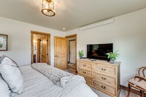 Ein Schlafzimmer mit Bett, Holzschrank, Fernseher und einer Pflanze.