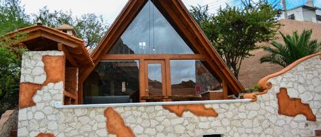 Un bâtiment en pierre avec un toit triangulaire en bois et de grandes fenêtres.