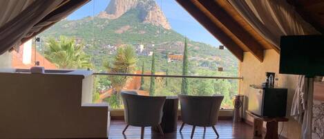 Un dormitorio con vista a la montaña, un balcón con sillas y una cama.